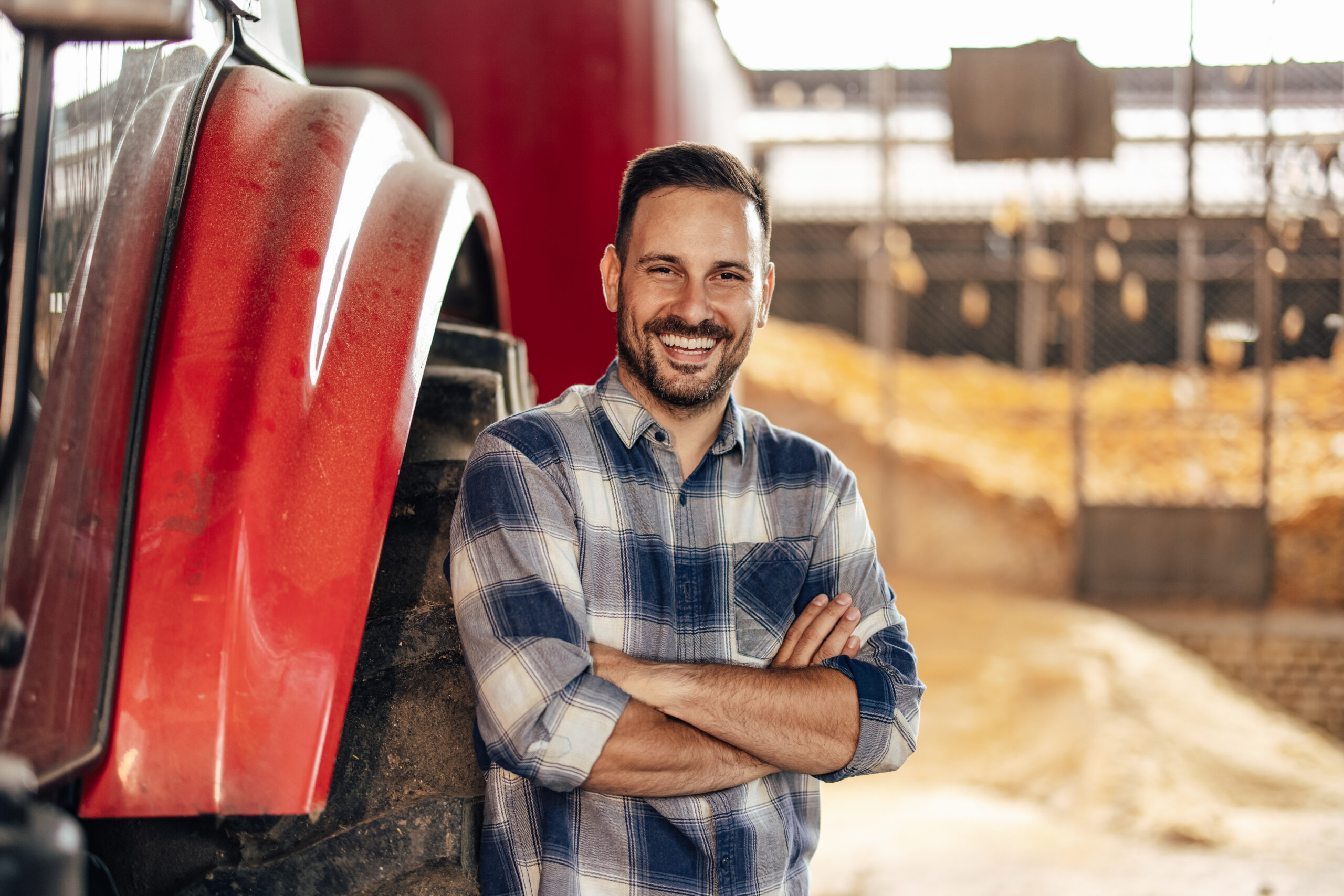 Portrait of adult man, leaning on the tractor tire, before work.